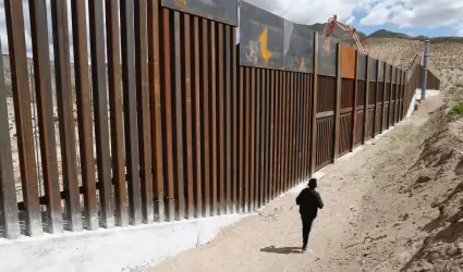 Migrante en el muro fronterizo