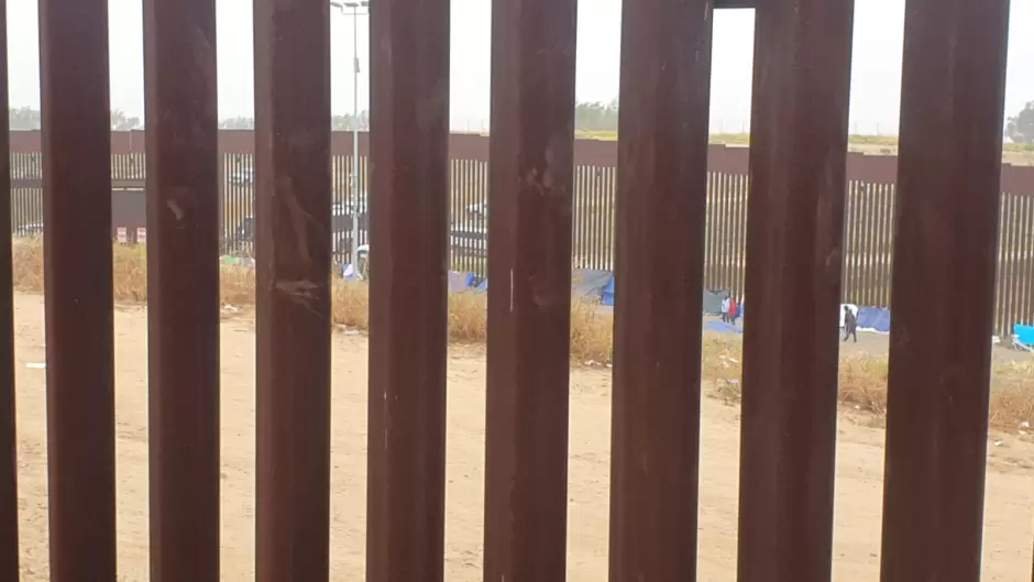 Migrantes en el muro fronterizo