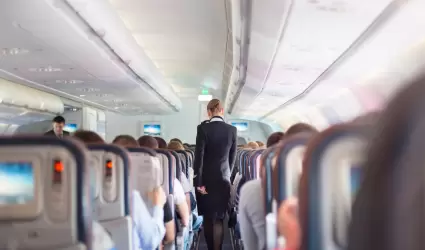 Azafata. Interior del avión con pasajeros en asiento durante el vuelo.