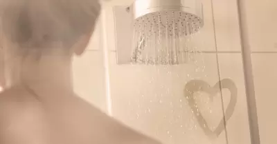 Mujer en ducha con un corazón de amor en el vapor del mampara de ducha.