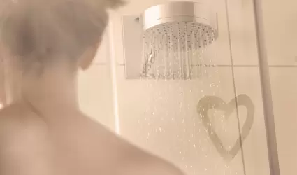 Mujer en ducha con un corazón de amor en el vapor del mampara de ducha.