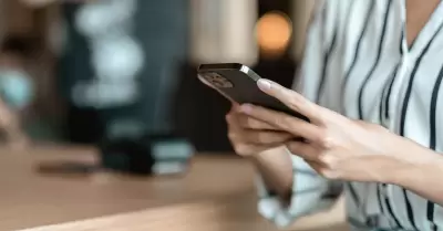 mujer usando un smartphone en una cafetera