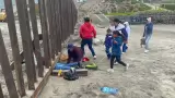 Familia con niños escarba arena para cruzar muro fronterizo y entregarse